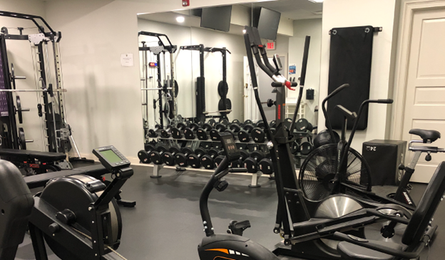 A well-equipped gym at the Leewood Golf Club, featuring weight machines, free weights, and cardio equipment.