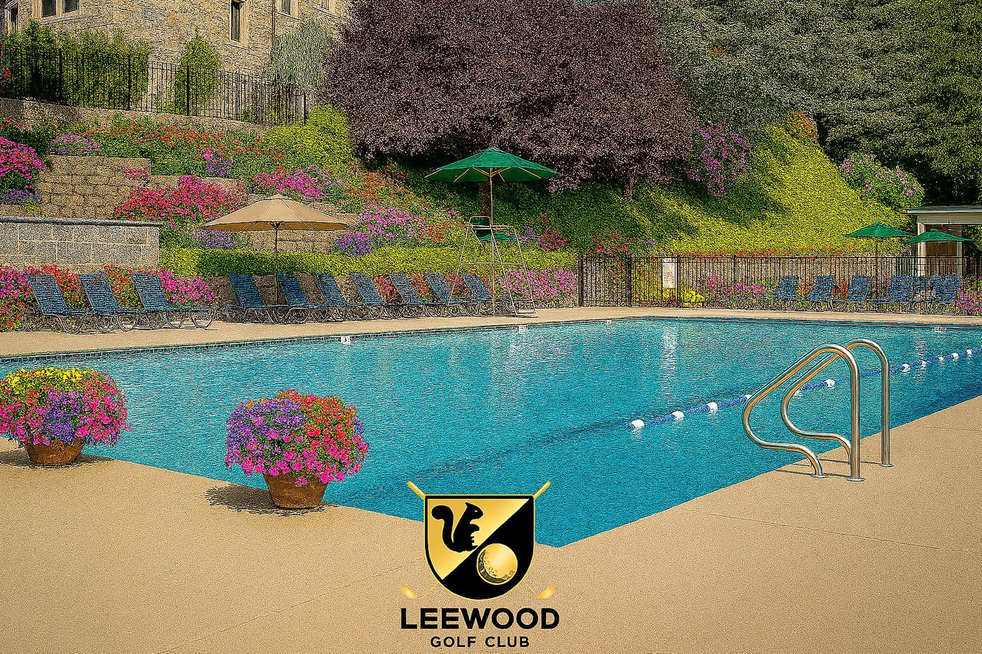 Swimming pool at Leewood Golf Club, surrounded by landscaping, umbrellas, and fencing.