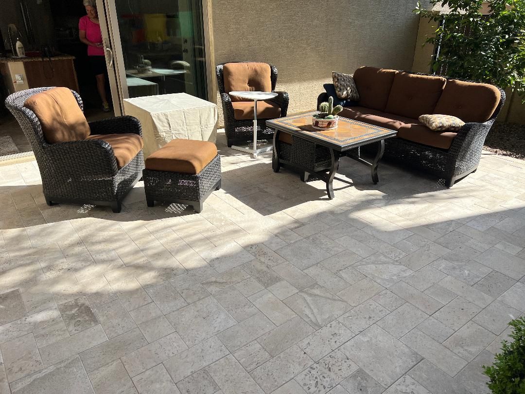 A patio with a couch, chairs, ottoman and table