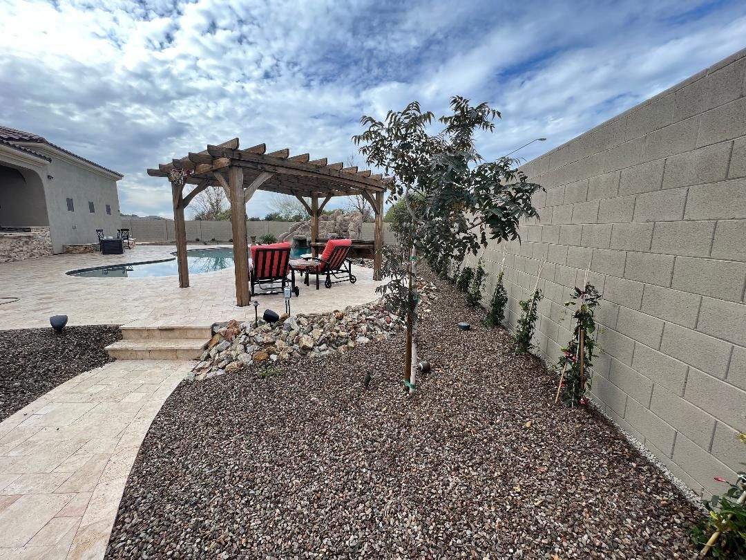 A walkway leading to a swimming pool with a pergola and chairs.