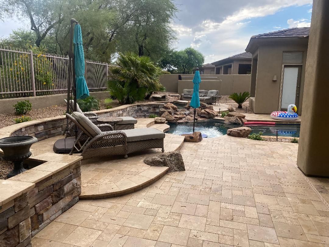 A patio with chairs, umbrellas and a pool in the backyard of a house.