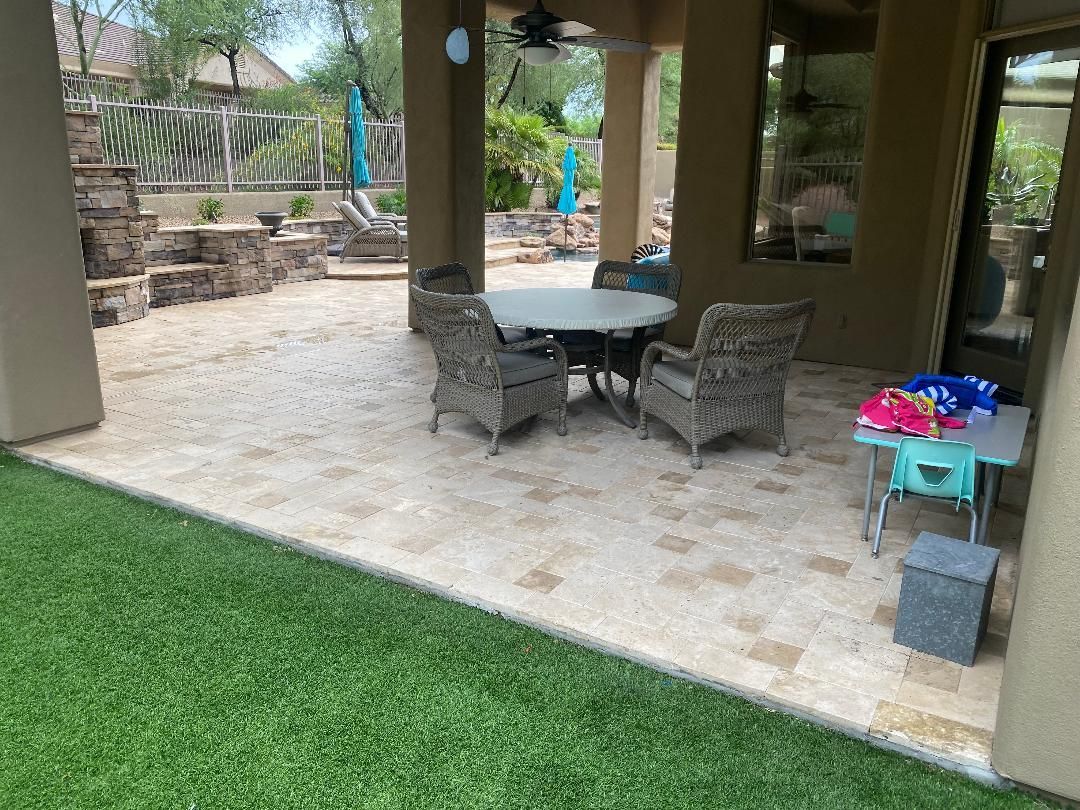 There is a table and chairs on the patio in the backyard.