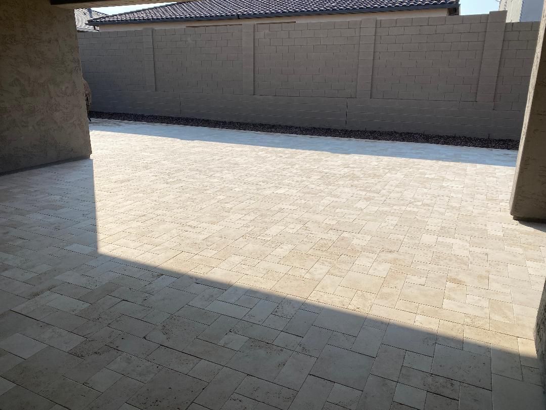 A patio with a brick wall and a shadow on the floor.