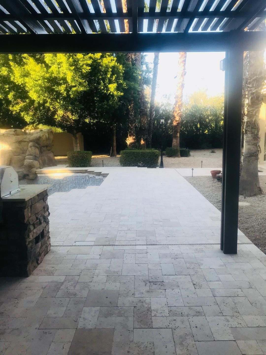 A patio with a pergola over it and trees in the background