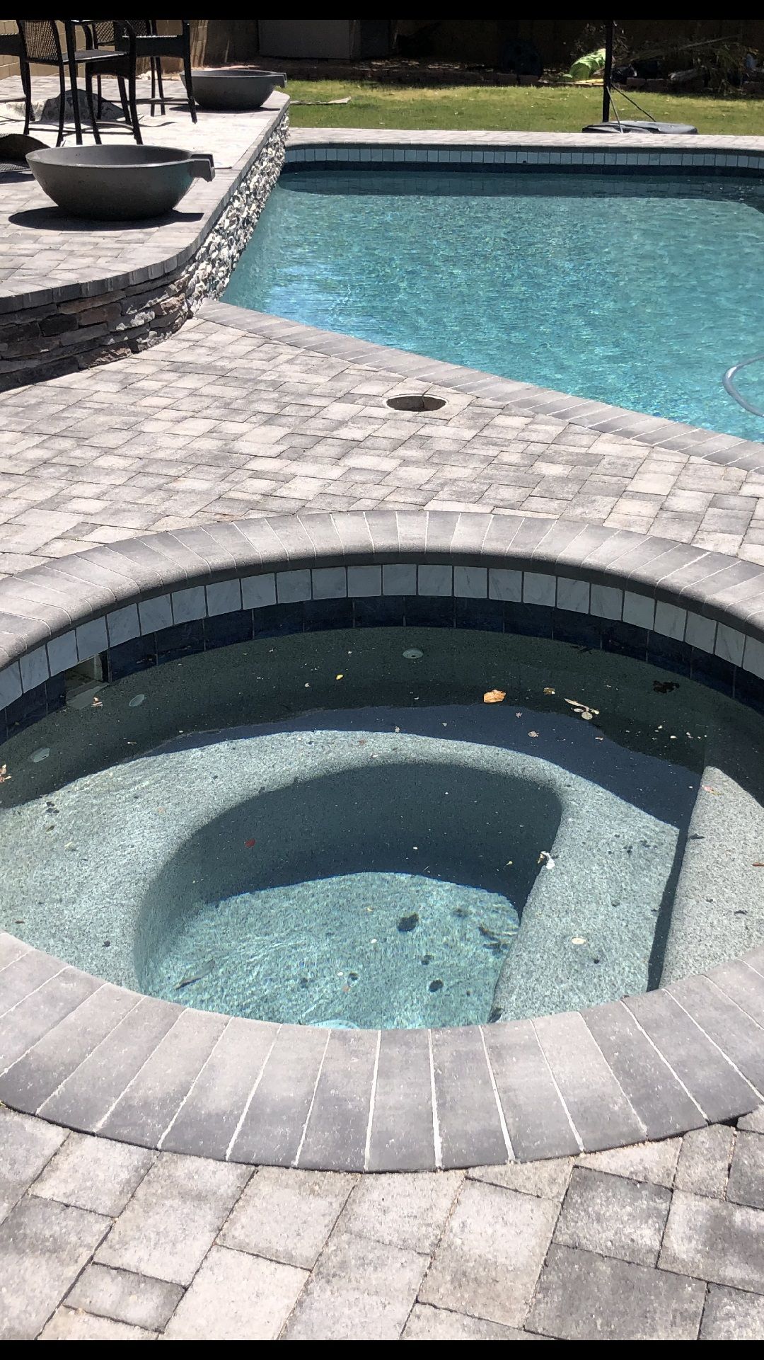 A hot tub is sitting next to a large swimming pool.