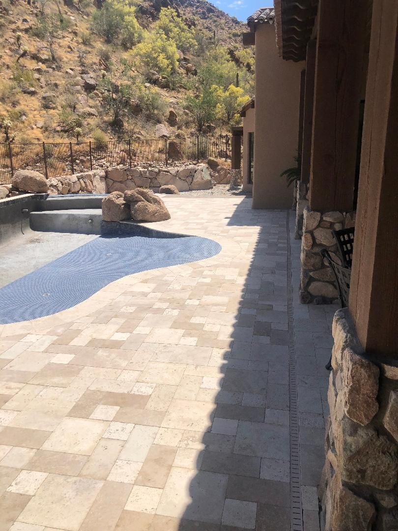 A patio with a pool in the background and a building in the background.
