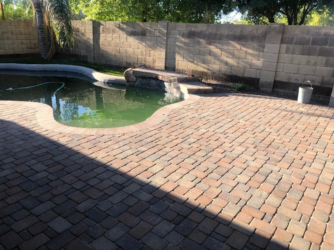 A brick patio with a swimming pool in the background.