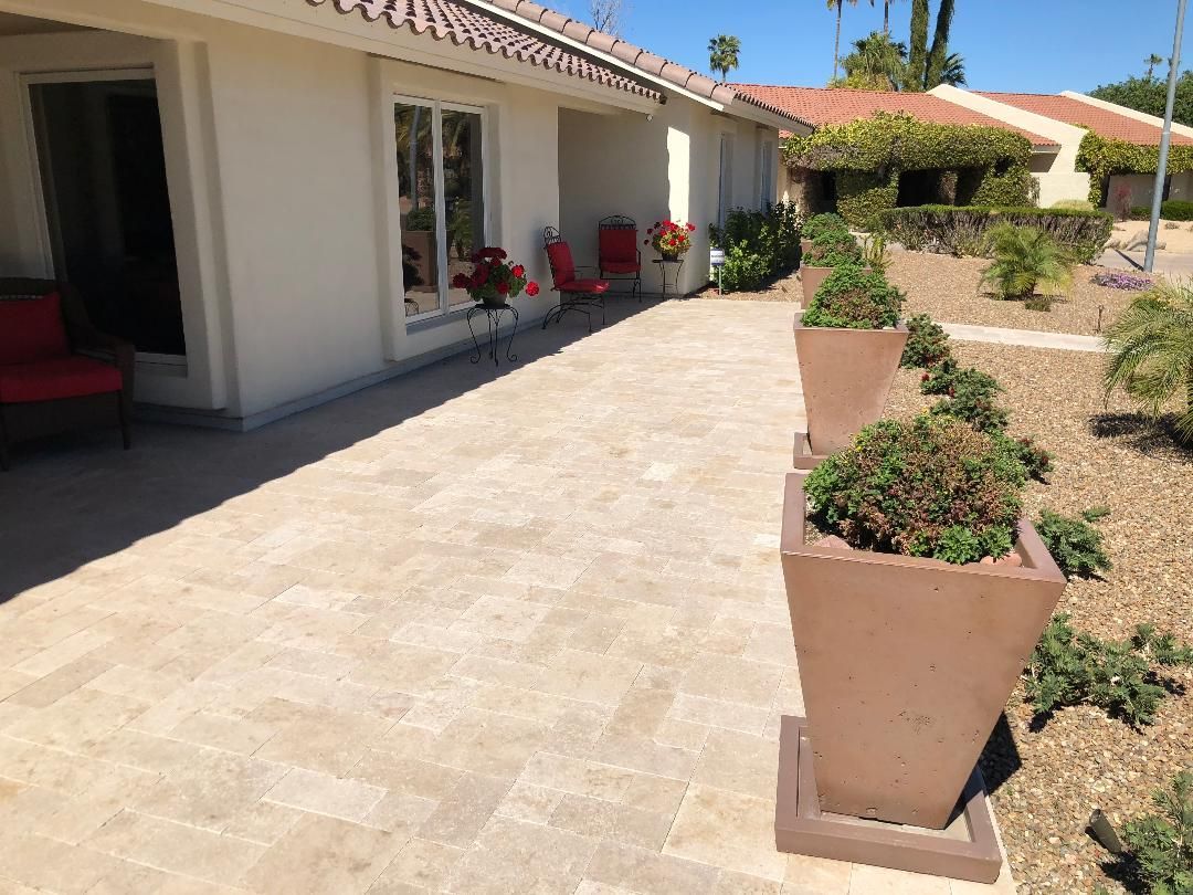 A patio with planters and chairs in front of a house.