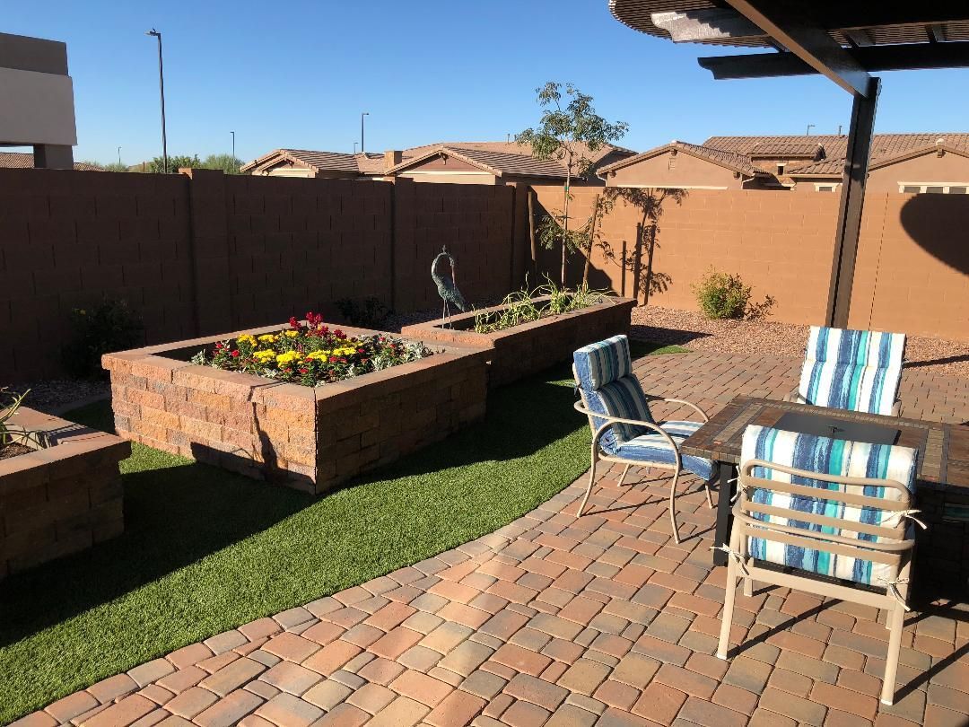 A patio with a table and chairs and a garden in the backyard