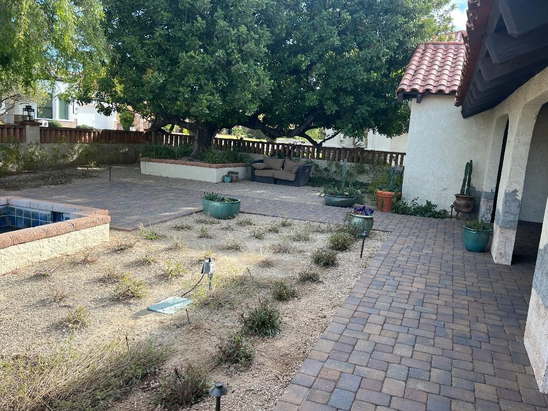 A backyard with a brick walkway and a fountain.