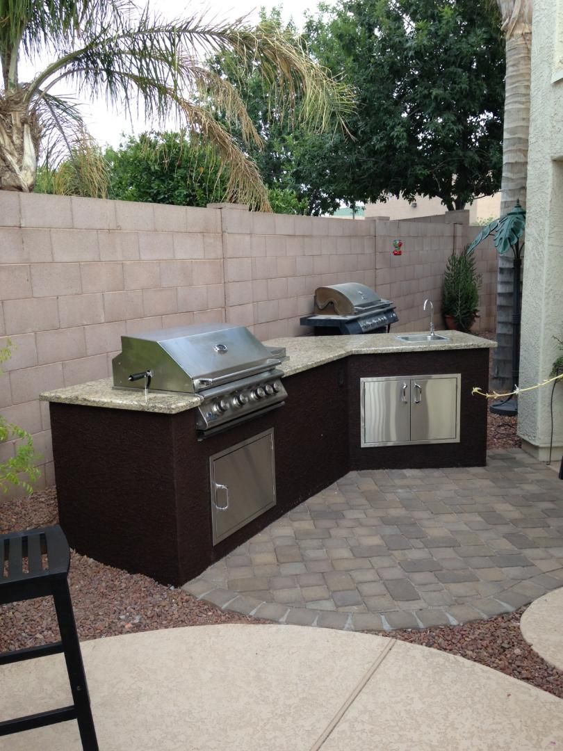 An outdoor kitchen with a grill and a sink