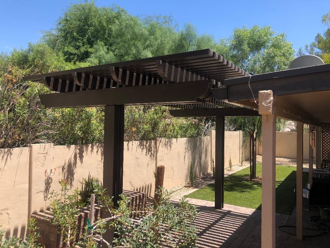 There is a pergola in the backyard of a house.
