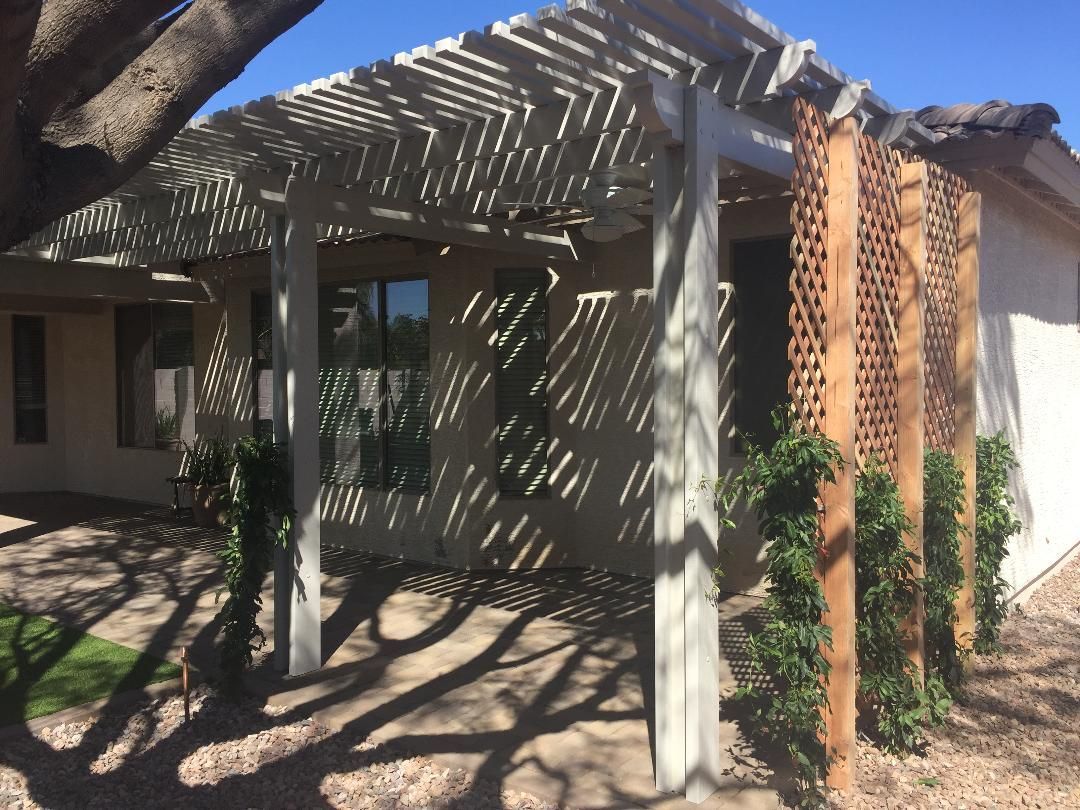 A house with a pergola and a tree in front of it