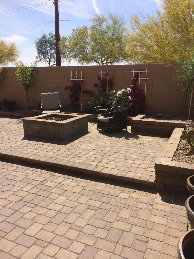A brick patio with a fire pit in the middle