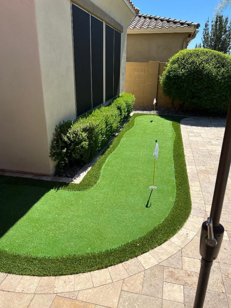There is a putting green in the backyard of a house.