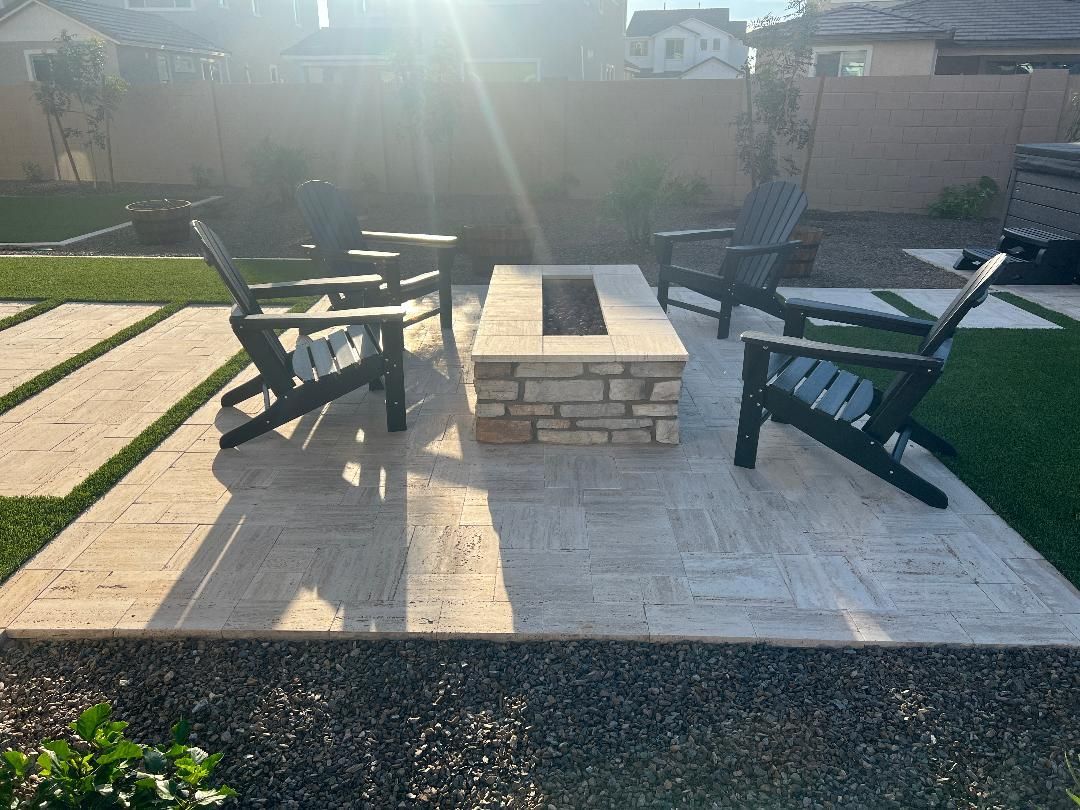 Two chairs are sitting next to a fire pit in a backyard.