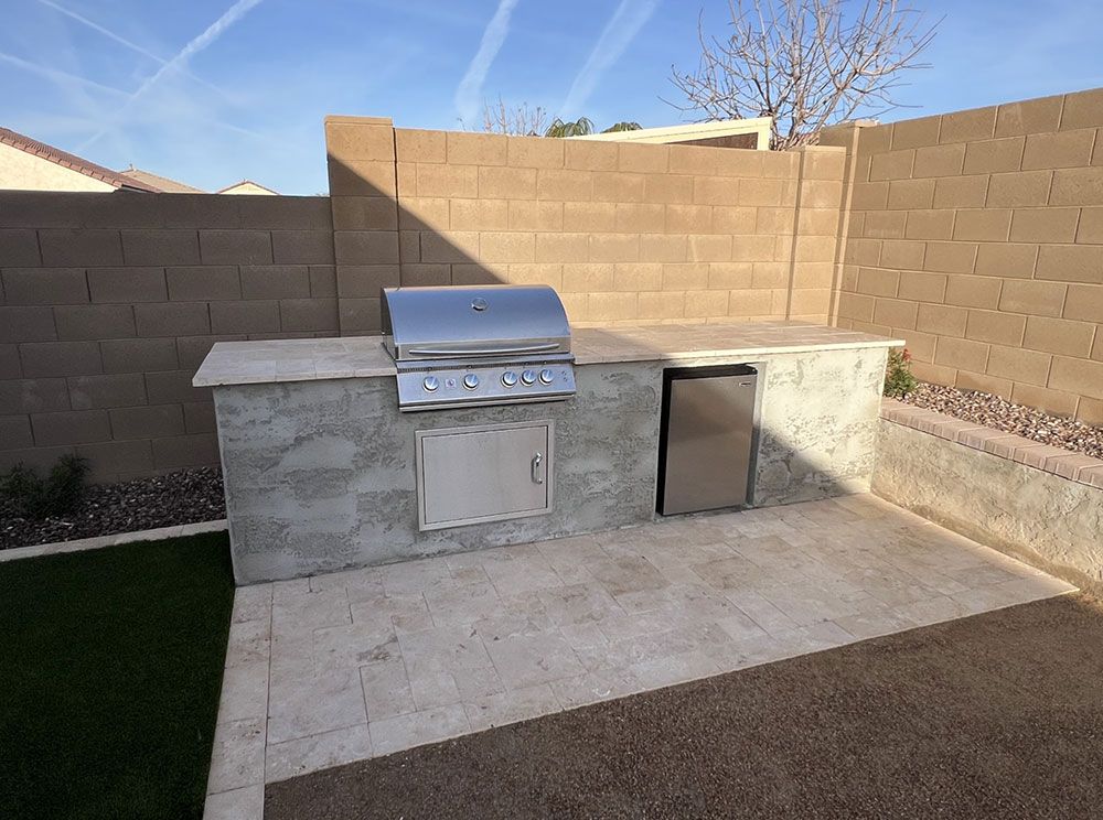 There is a grill and a refrigerator in the backyard.