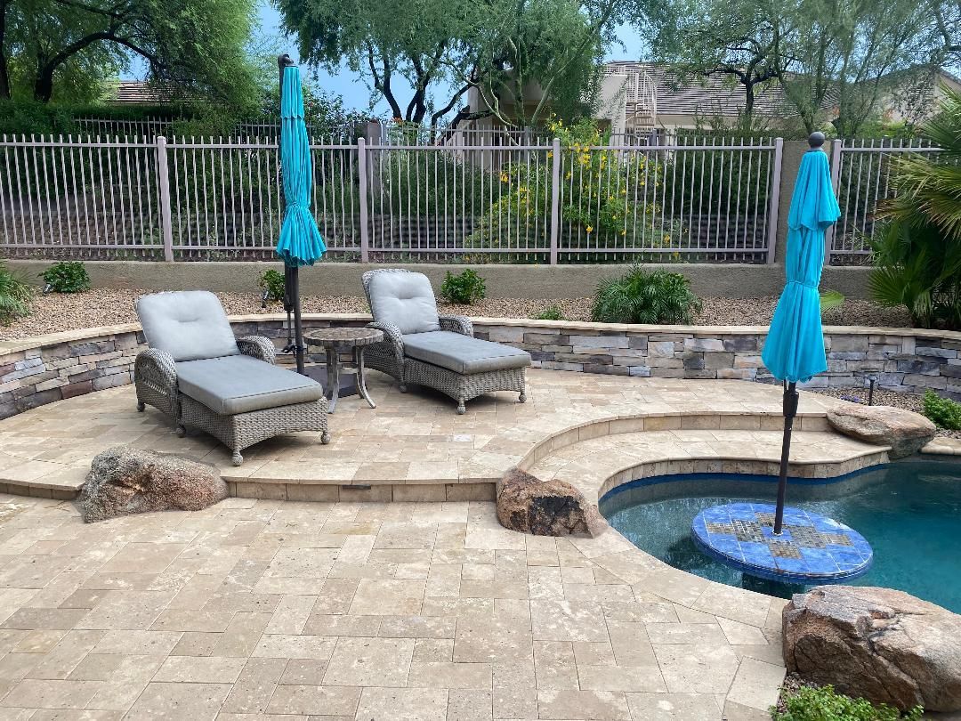 A patio with chairs and umbrellas next to a pool.