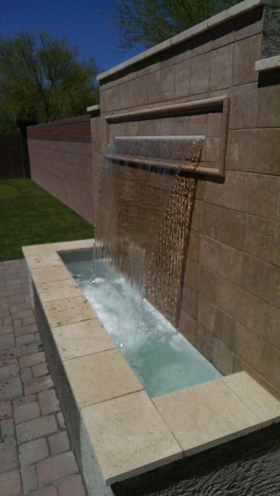 A waterfall is built into the side of a brick wall.