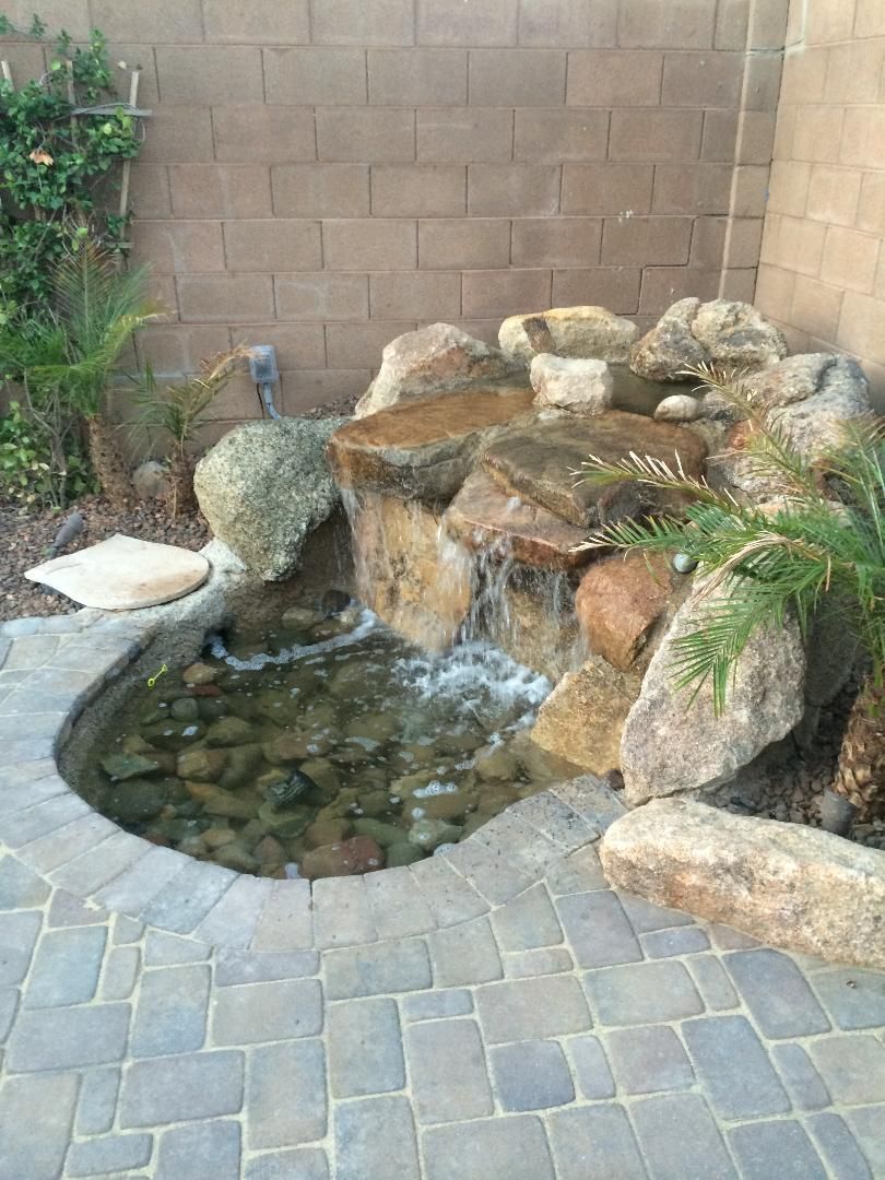 There is a waterfall in the middle of a pond surrounded by rocks.