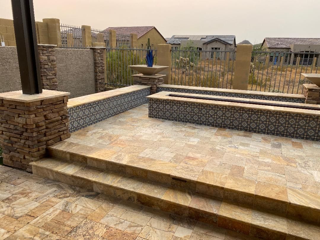 A stone patio with stairs leading up to a pool.