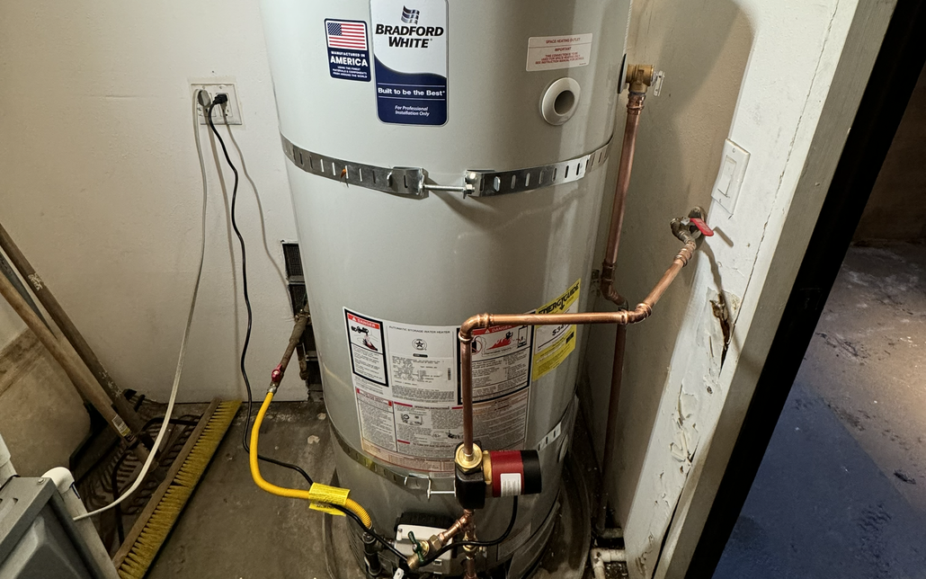 Water heater in a utility closet with exposed wires and yellow gas line attached.