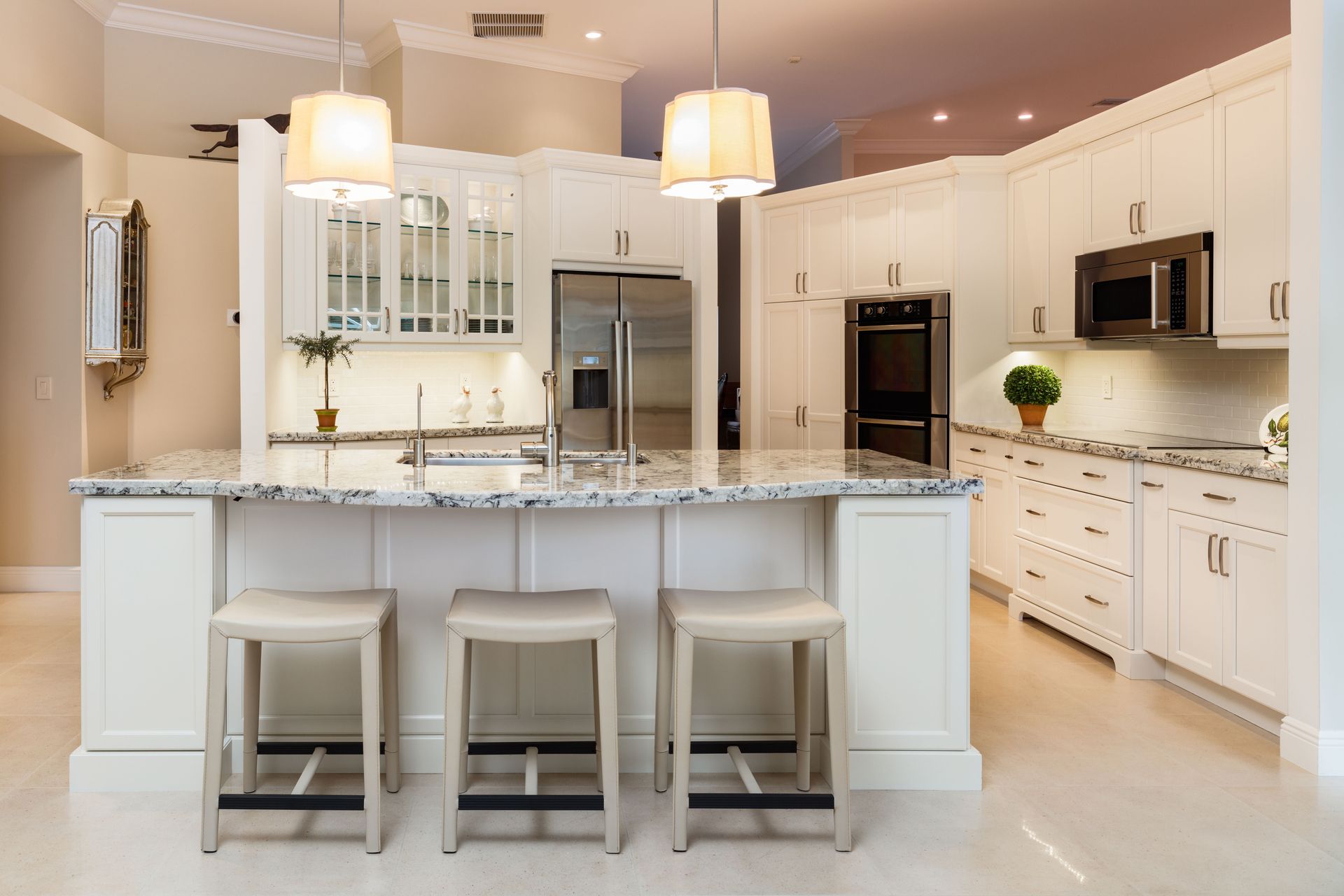 White kitchen with granite countertops, stainless steel appliances, and bar stools.
