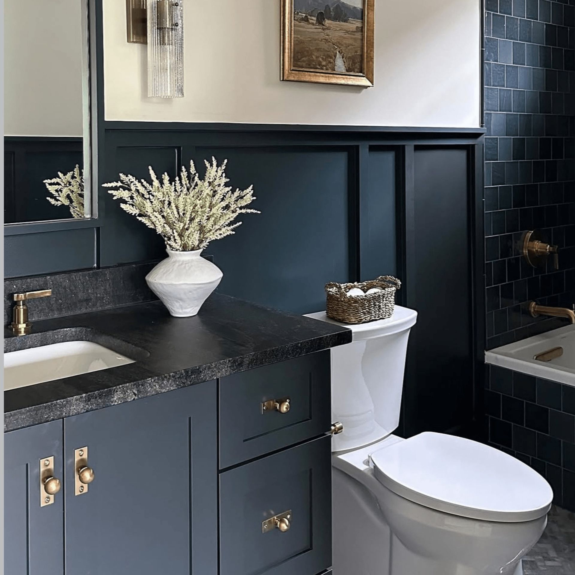 Navy blue bathroom with black countertop, white toilet, and gold accents.