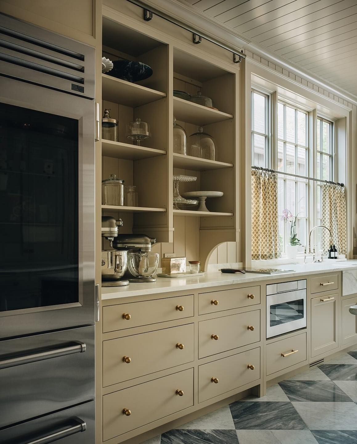 Cream kitchen with built-in cabinetry, marble floor, and large stainless steel refrigerator.