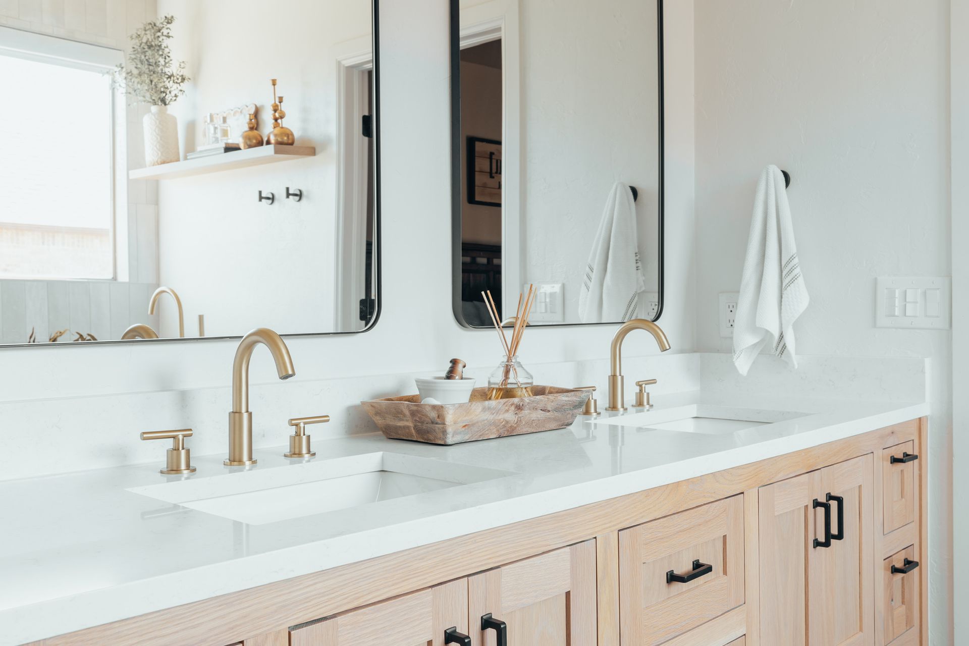 Modern bathroom with gold fixtures, white countertop, and light wood vanity.