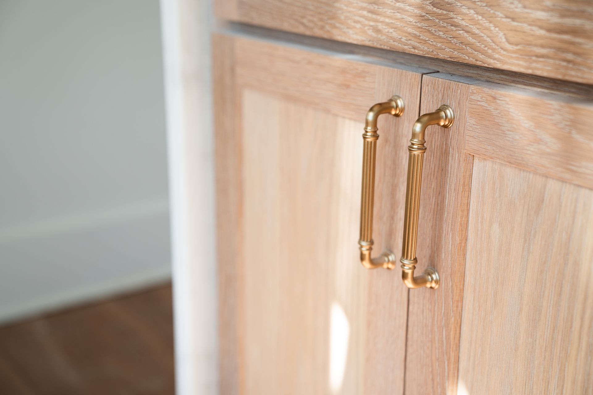 Close-up of light wooden cabinet doors with gold handles.