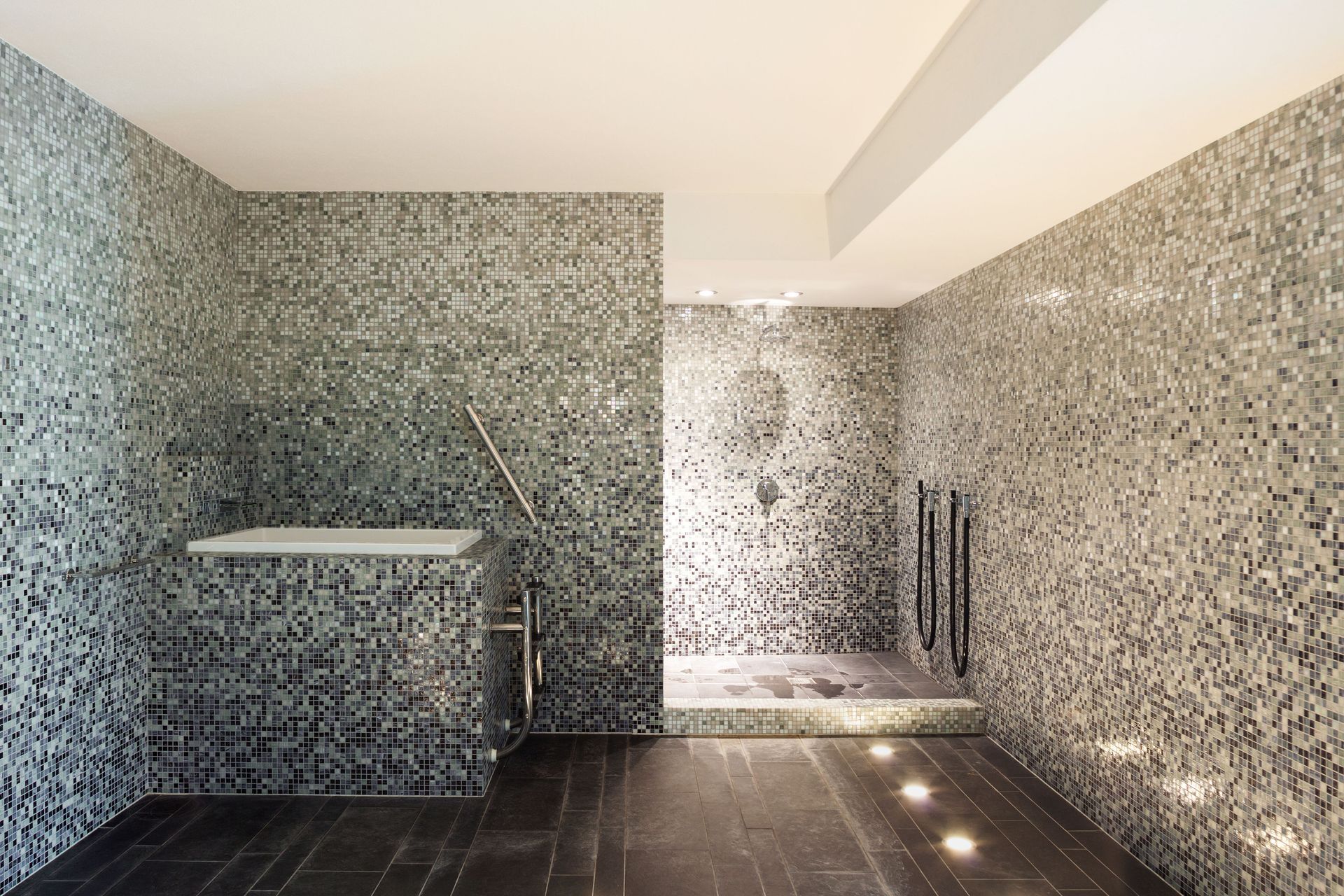 Modern bathroom with mosaic tile walls, dark floor, and shower.