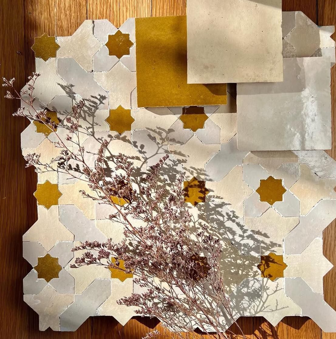 Mosaic tile with gold stars and squares, dried flowers; neutral tones.