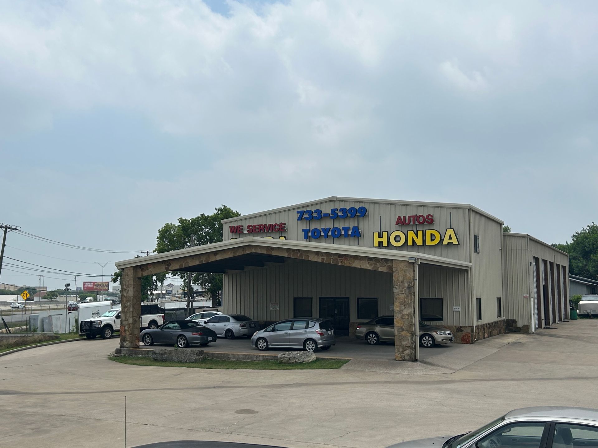 Auto repair shop, "VC Auto Honda," with vehicles parked out front.