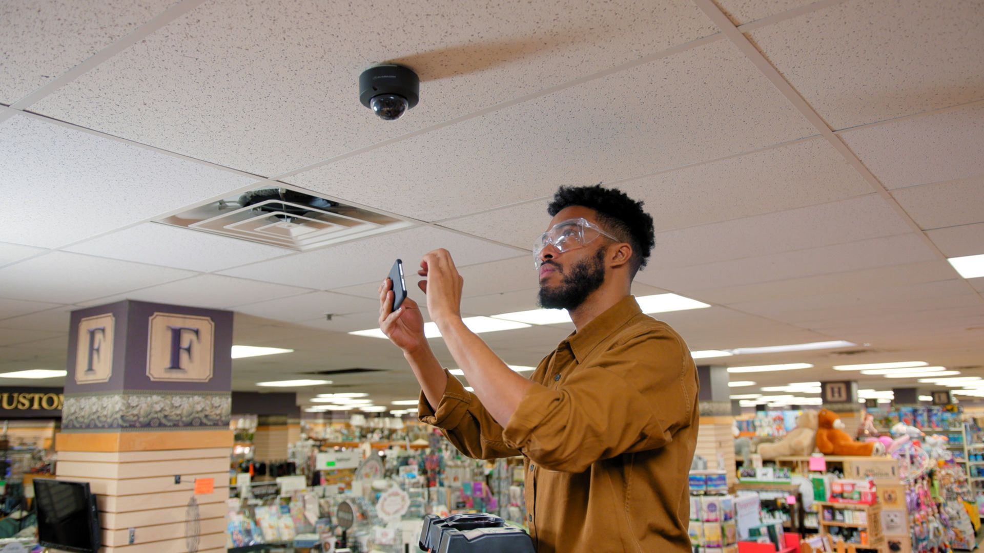 A man is taking a picture of the ceiling of a store.