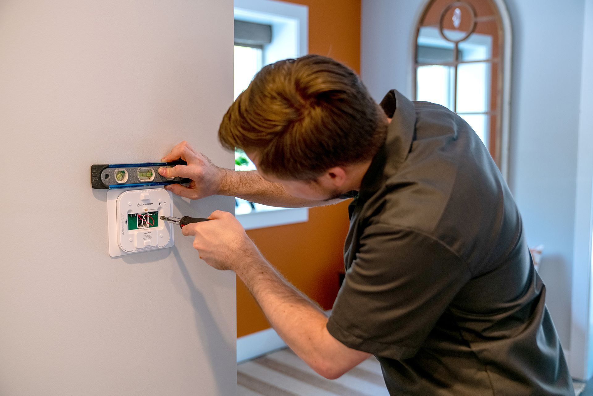 A man is working on a wall with a level and screwdriver.