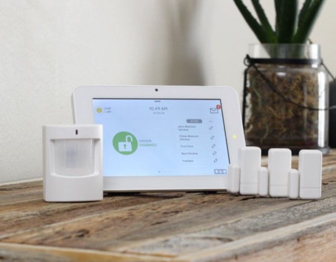 A security system is sitting on a wooden table next to a plant