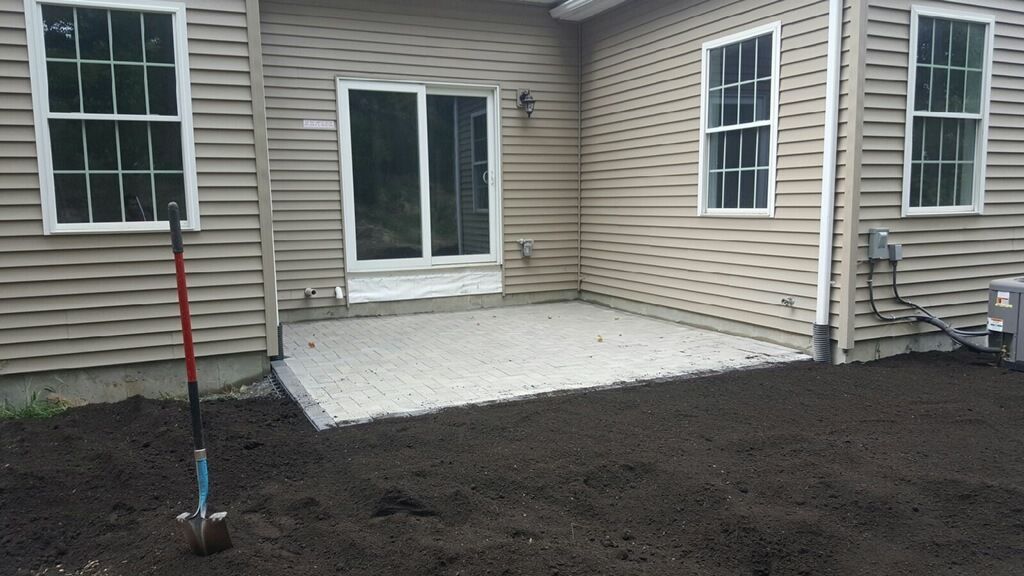 A house with a patio and a shovel in front of it
