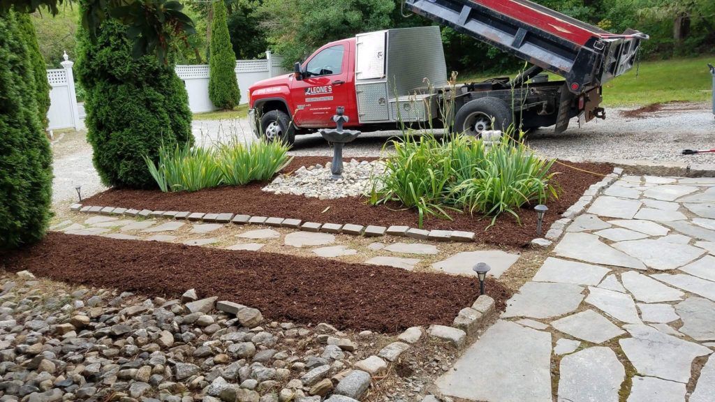 A red dump truck is parked in a driveway next to a stone walkway.