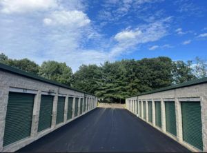 A row of green storage units are lined up on the side of a road.