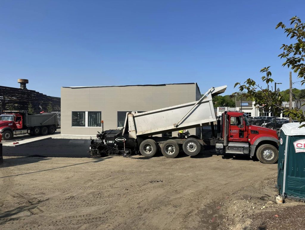 A dump truck is parked in a dirt lot in front of a building.