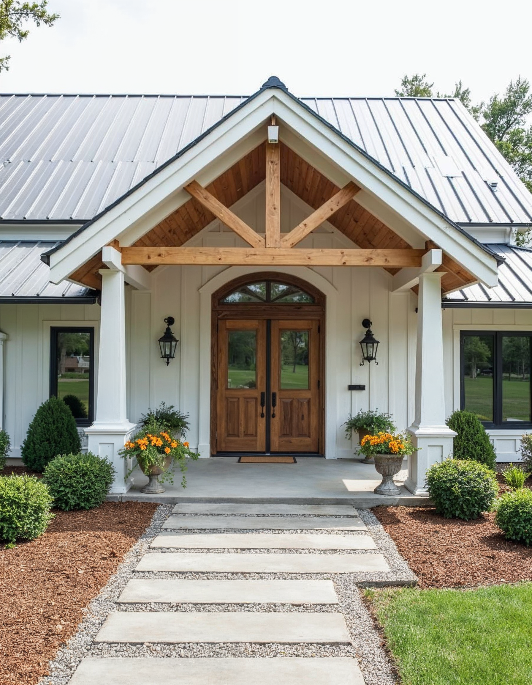White farmhouse entrance with wooden double doors under a gabled porch; stone walkway and landscaping.