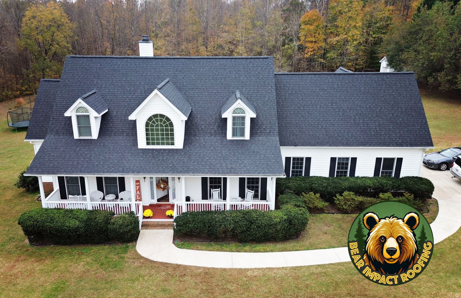 A white house with a dark roof and a front porch. A 