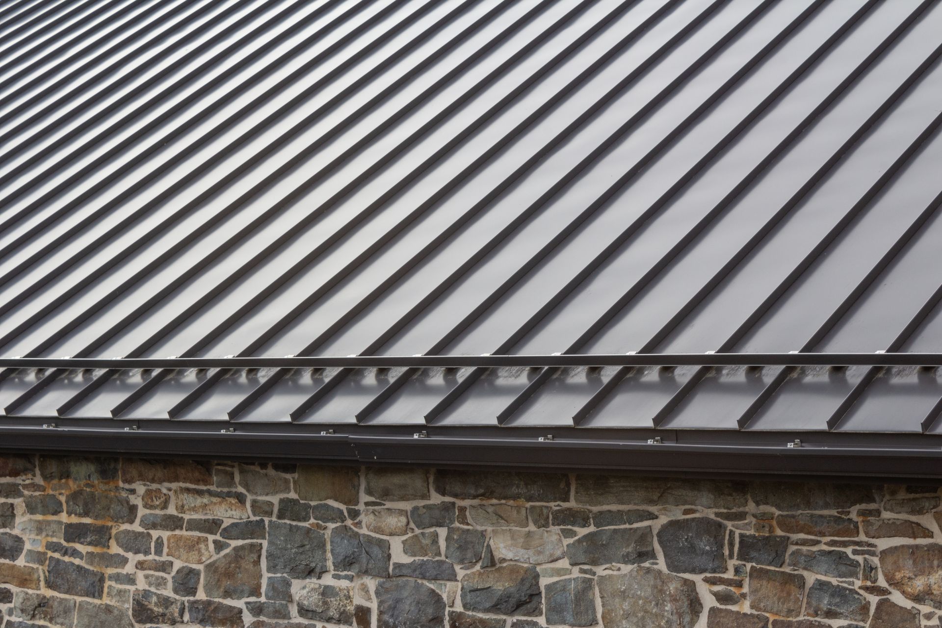 Dark gray metal roof on a stone building.