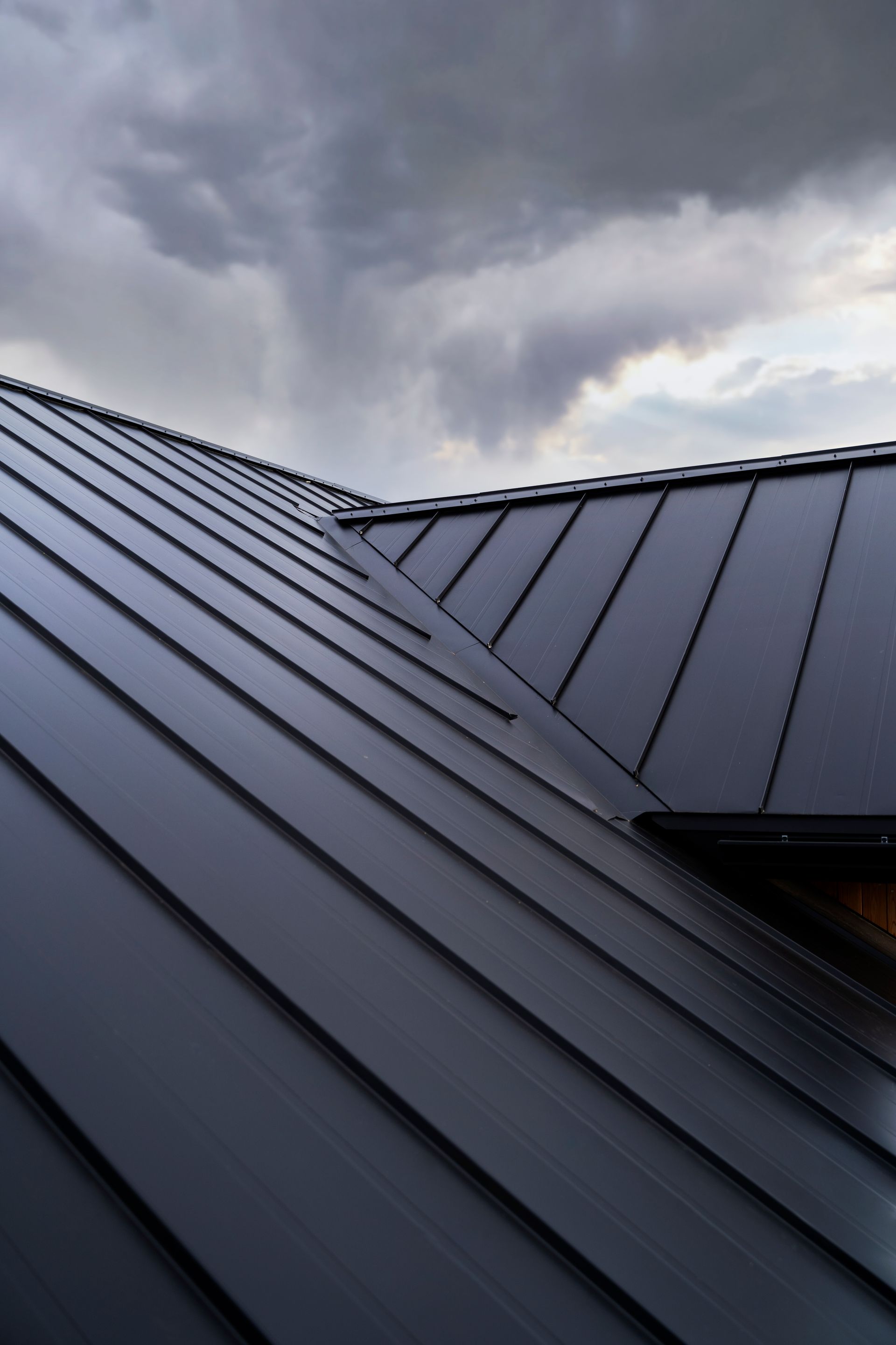 Black metal roof under a stormy, cloudy sky.