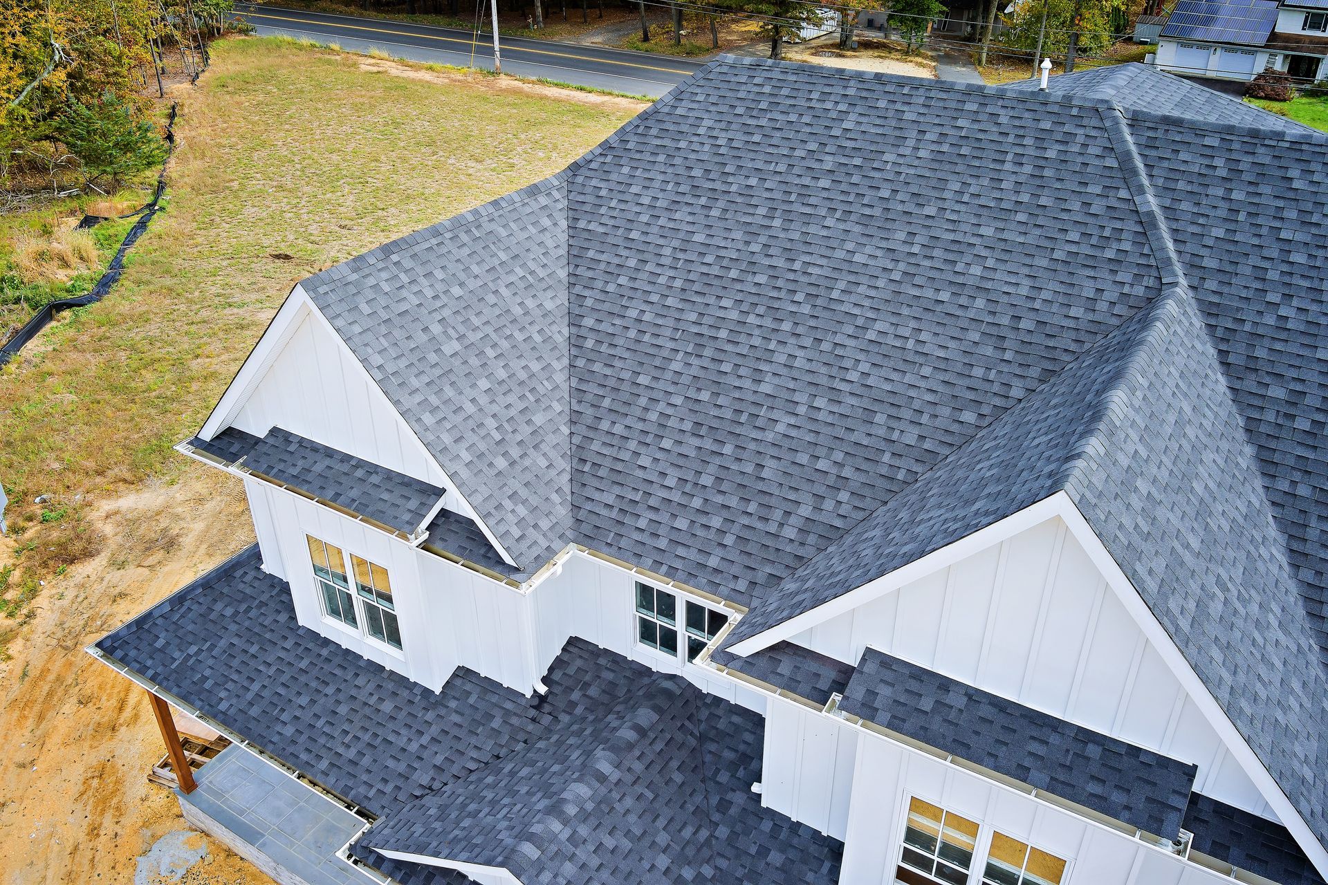 White house with a dark gray shingled roof, set on a grassy lot.
