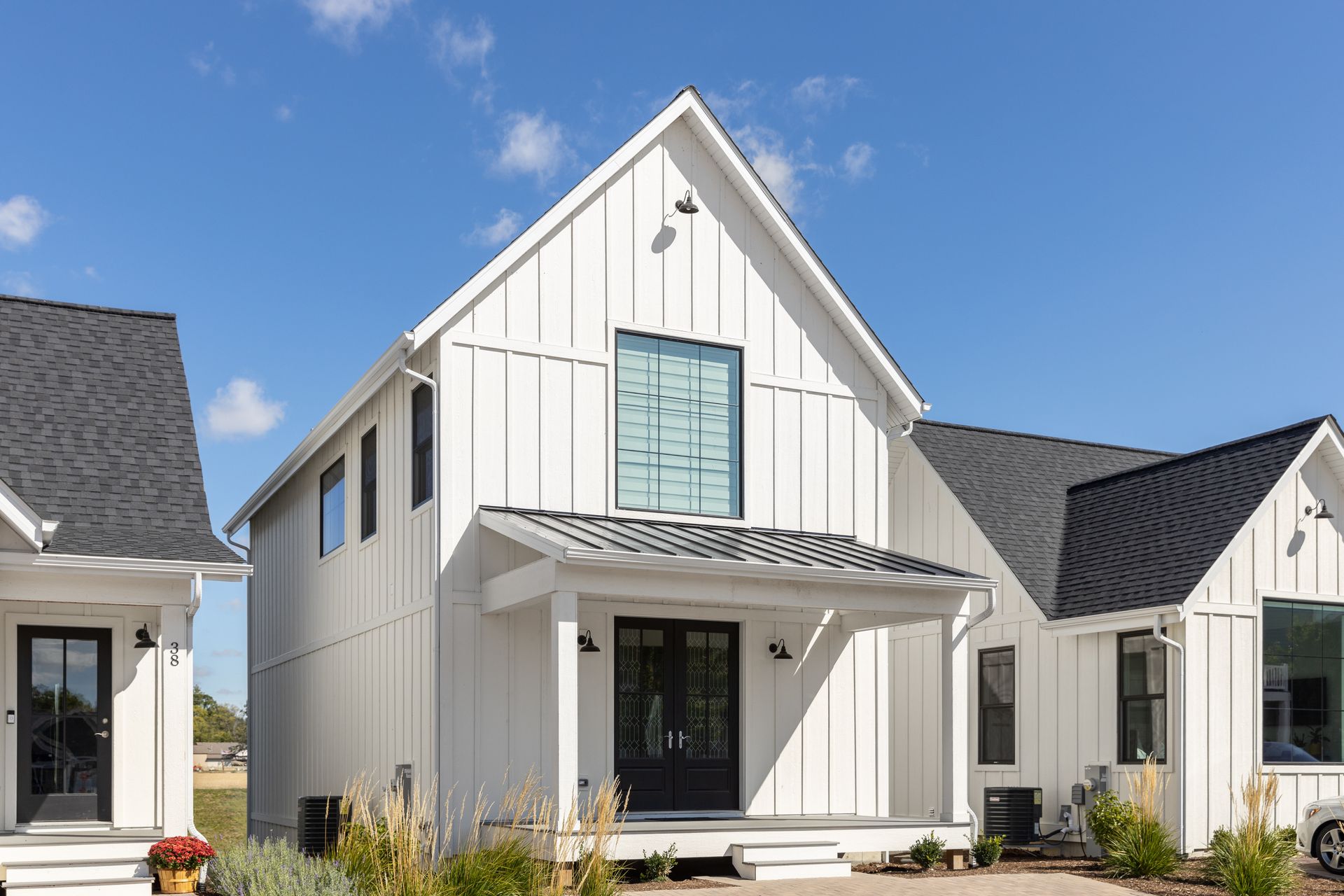 White modern farmhouse style homes with black trim and a blue sky.