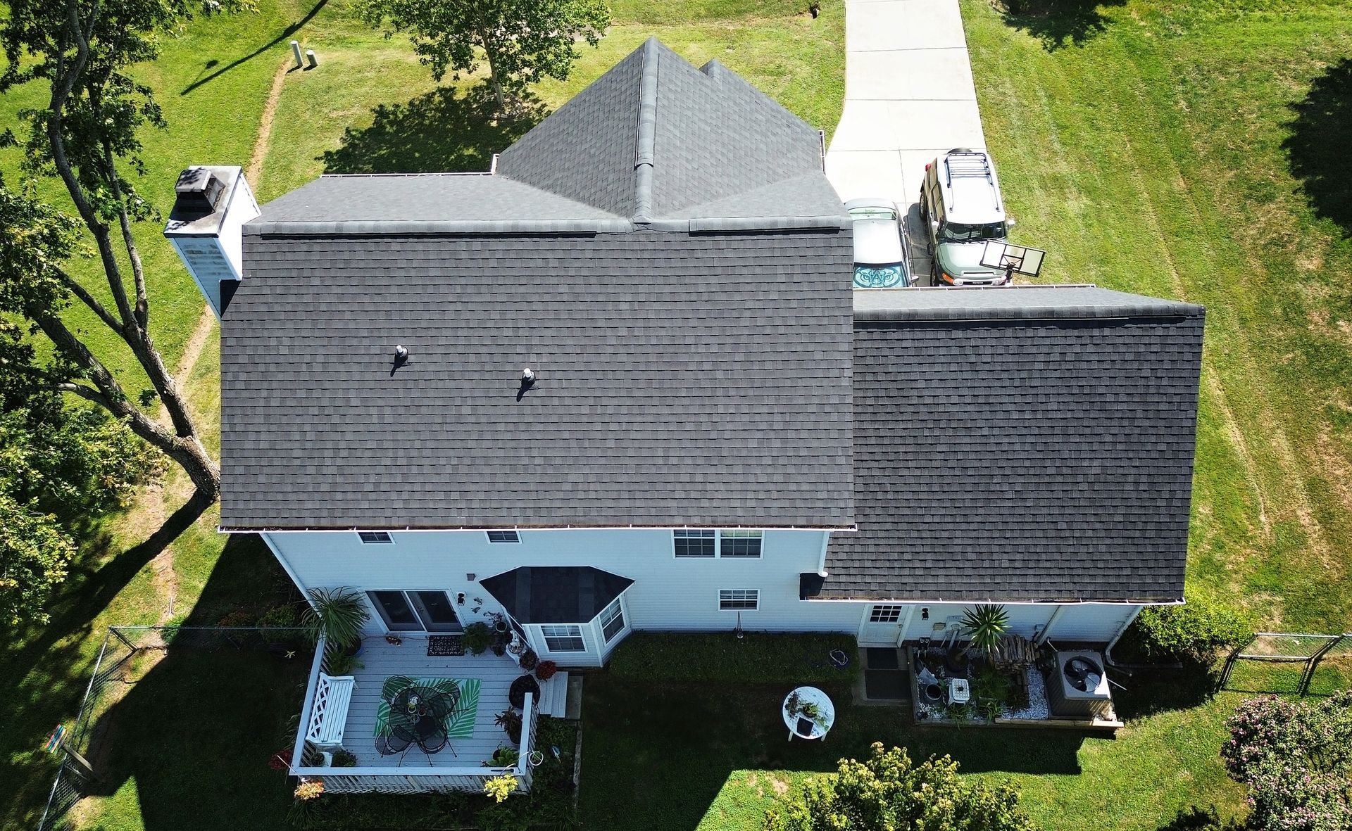 Overhead view of a two-story white house with a gray roof and a driveway.