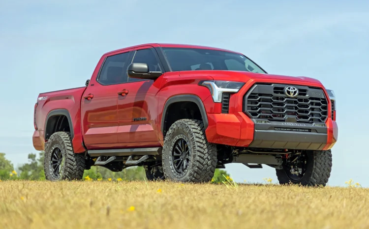 a red toyota tundra is parked in a field .