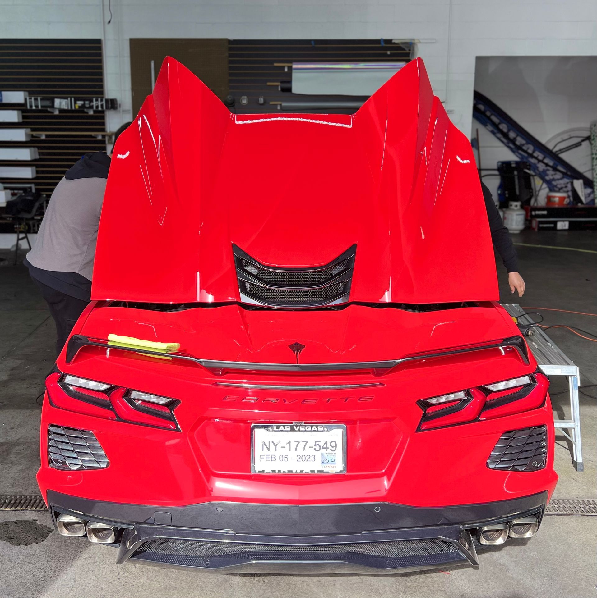a red sports car with the hood open in a garage